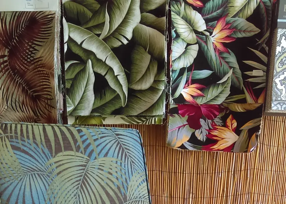 Tropical fabric samples in palm, banana leaf and bird of paradise prints hanging on the shop's bamboo-mat wall