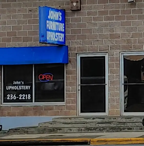 The shop front with the John's Upholstery 236-2218 window sign and the OPEN neon lit